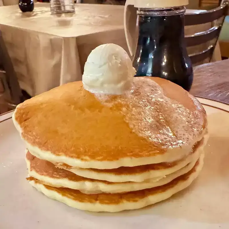 pouring syrup on stack of pancakes